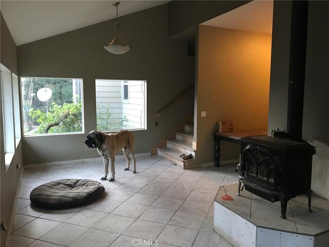 living room featuring lofted ceiling, a wood stove, and light tile patterned floors