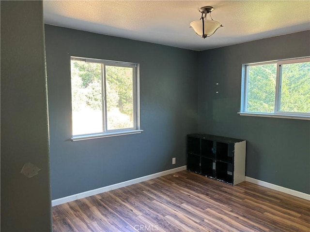 empty room featuring a textured ceiling and dark wood-type flooring
