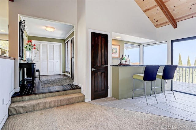 interior space featuring beam ceiling, light colored carpet, high vaulted ceiling, and wood ceiling