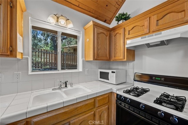 kitchen featuring white appliances, sink, lofted ceiling, backsplash, and tile countertops