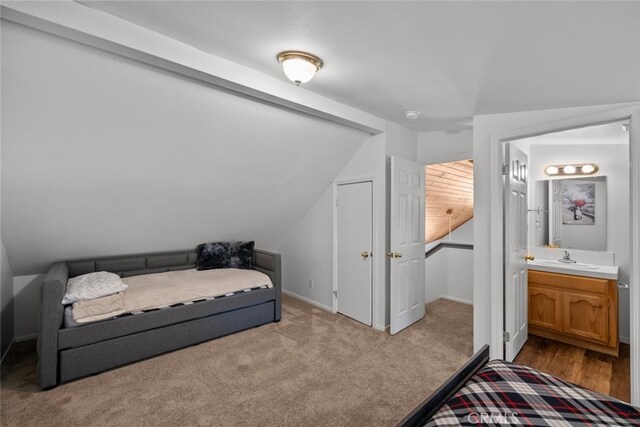 carpeted bedroom featuring sink, connected bathroom, and vaulted ceiling