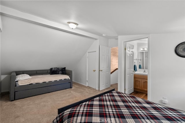 bedroom featuring light colored carpet, lofted ceiling, and ensuite bathroom