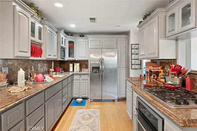 kitchen featuring backsplash, gray cabinets, light wood-type flooring, and stainless steel appliances