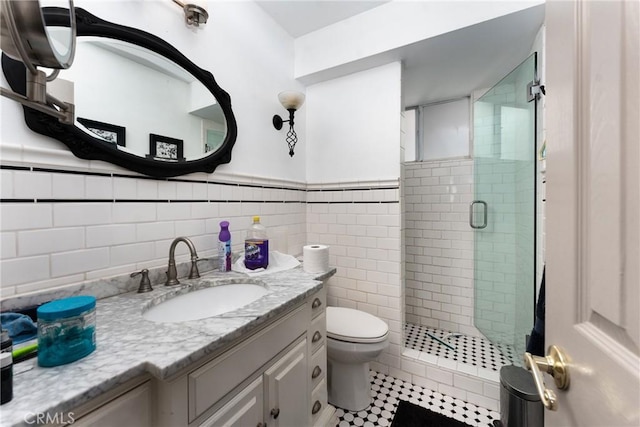 bathroom featuring vanity, toilet, tile walls, and a shower with shower door