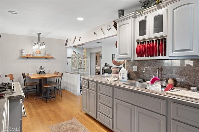 kitchen with gray cabinetry, decorative backsplash, light hardwood / wood-style floors, and pendant lighting