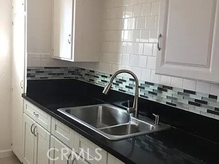 kitchen featuring decorative backsplash, white cabinets, and sink