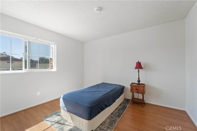 bedroom featuring hardwood / wood-style flooring and a textured ceiling