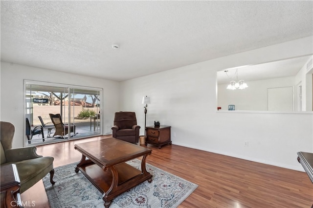 living room featuring hardwood / wood-style floors, a chandelier, and a textured ceiling