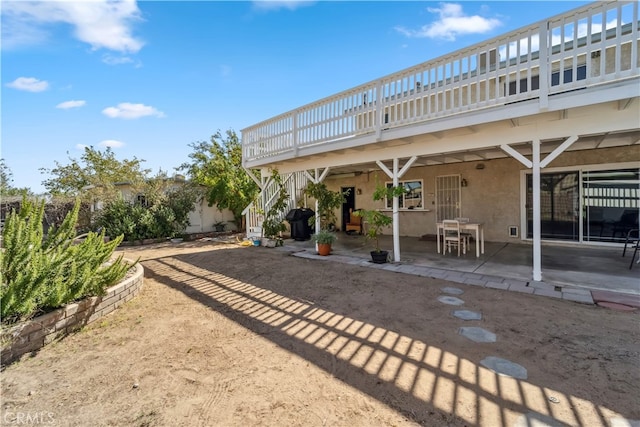 rear view of house with a wooden deck and a patio