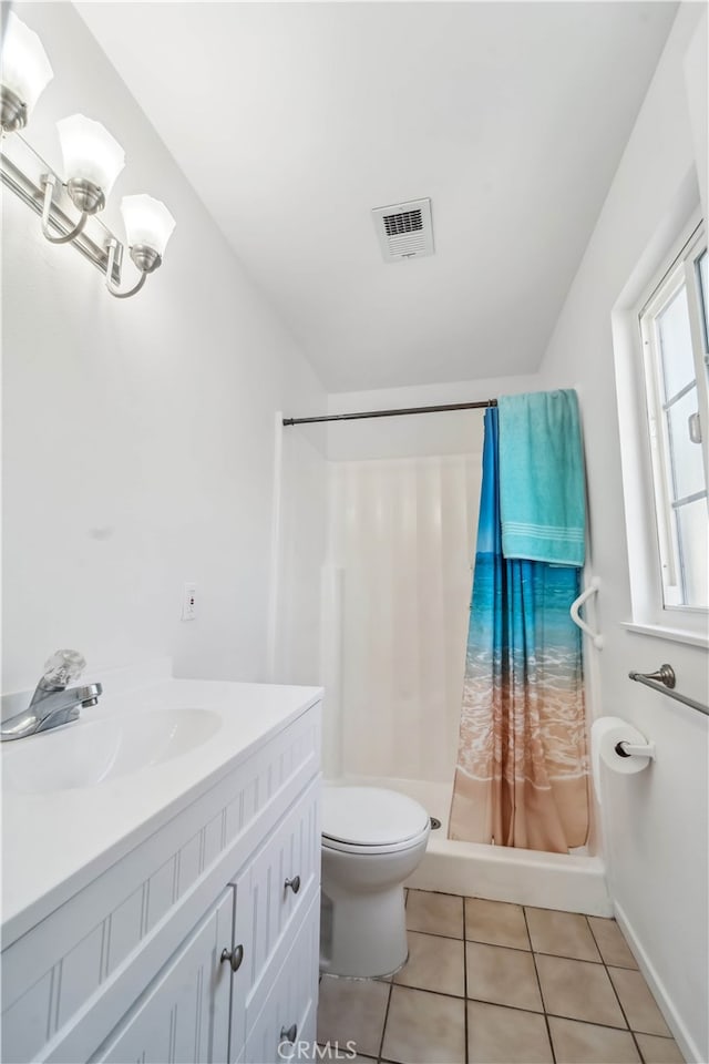 bathroom with tile patterned flooring, walk in shower, vanity, and toilet