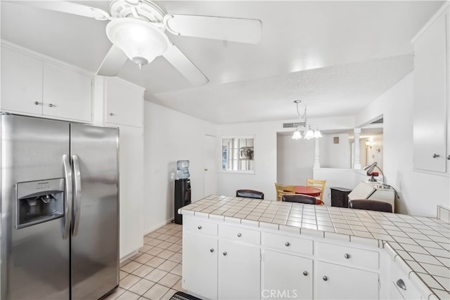 kitchen with pendant lighting, tile counters, stainless steel fridge with ice dispenser, and white cabinetry