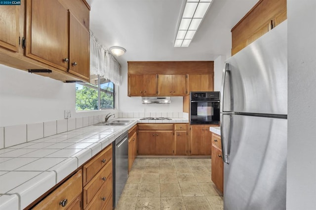 kitchen featuring tile counters, sink, and stainless steel appliances