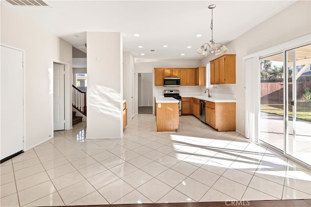 kitchen with light tile patterned flooring, hanging light fixtures, a kitchen island, appliances with stainless steel finishes, and a notable chandelier