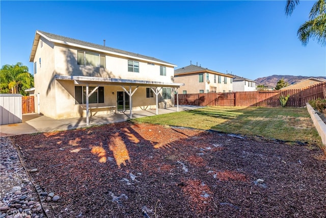 back of property featuring a patio, a yard, and a mountain view