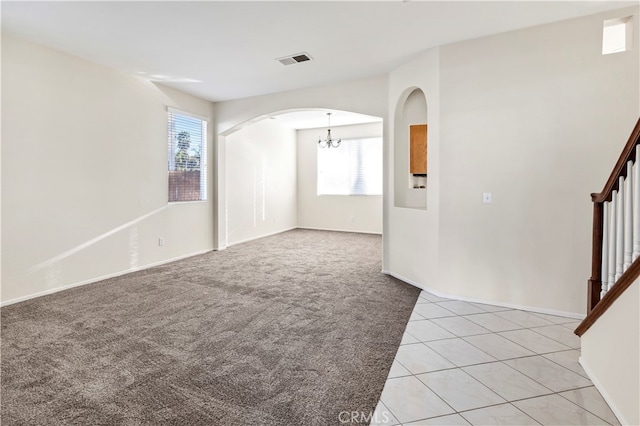 empty room featuring light colored carpet and a notable chandelier