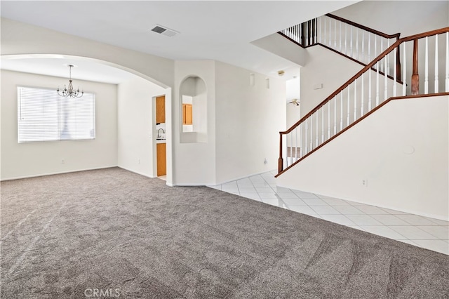 carpeted spare room featuring a notable chandelier