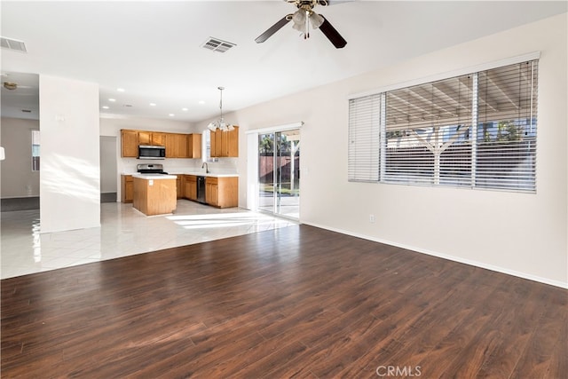 unfurnished living room featuring ceiling fan with notable chandelier, light wood-type flooring, and sink