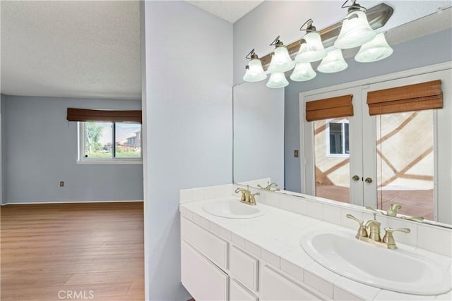 bathroom with hardwood / wood-style flooring, vanity, a textured ceiling, and french doors