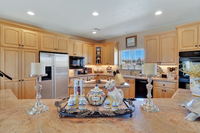 kitchen with light brown cabinets, backsplash, and black appliances