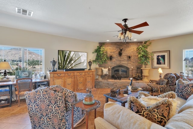 living room with a fireplace, light tile patterned floors, a wealth of natural light, and ceiling fan