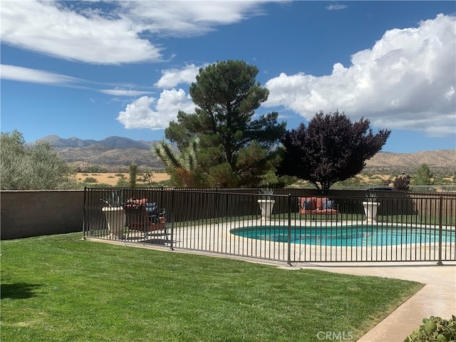 view of pool with a patio area, a lawn, and a mountain view