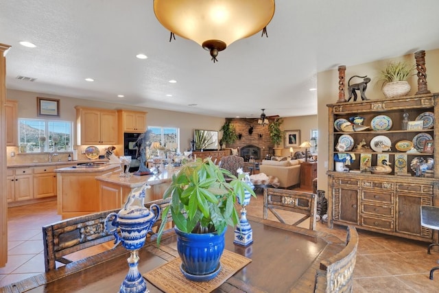 dining area featuring a brick fireplace, sink, light tile patterned floors, and a textured ceiling