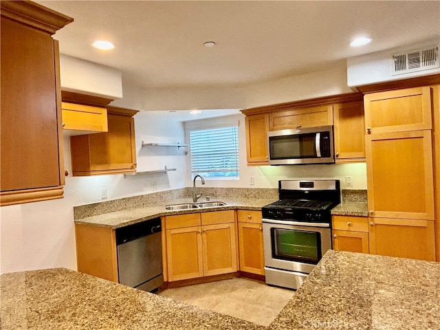 kitchen with light tile patterned floors, light stone countertops, sink, and stainless steel appliances