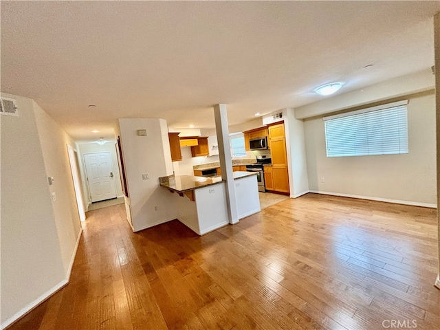 kitchen featuring kitchen peninsula, light hardwood / wood-style floors, and appliances with stainless steel finishes