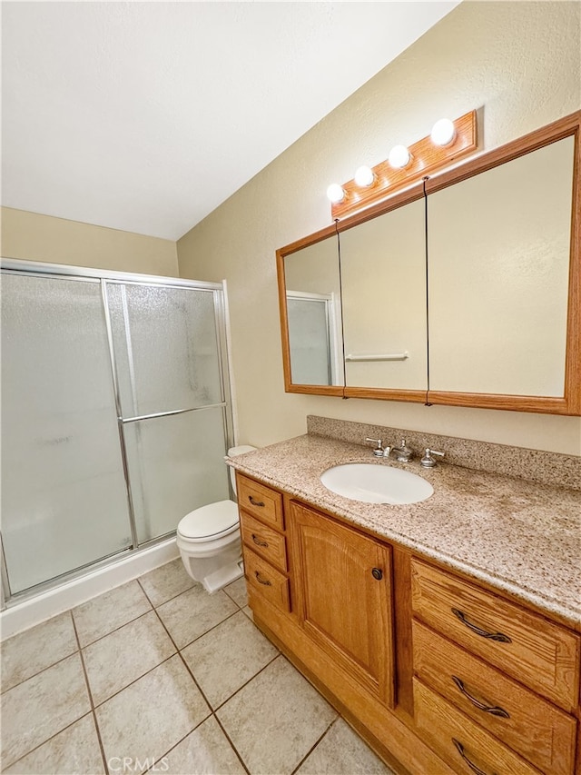 bathroom with a shower with door, tile patterned floors, vanity, and toilet