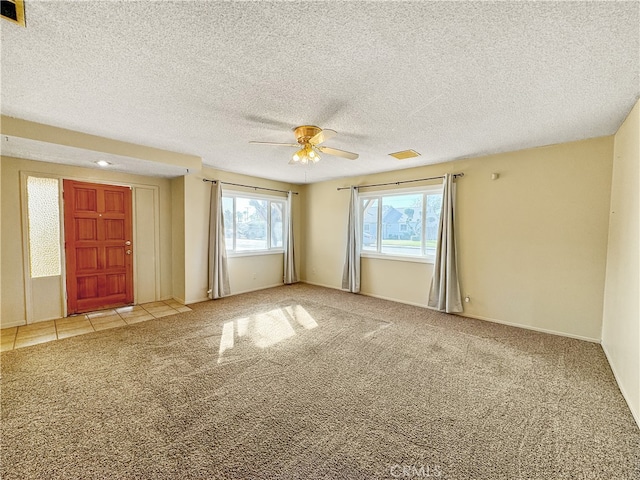 carpeted empty room featuring ceiling fan and a textured ceiling