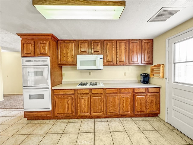 kitchen featuring white appliances, light tile patterned floors, and a textured ceiling