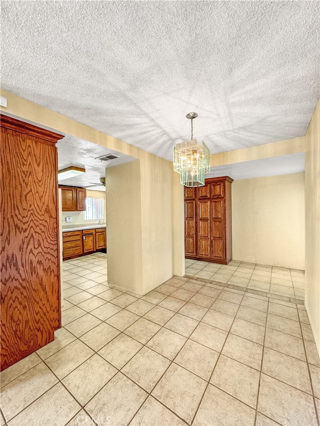 tiled spare room with an inviting chandelier and a textured ceiling