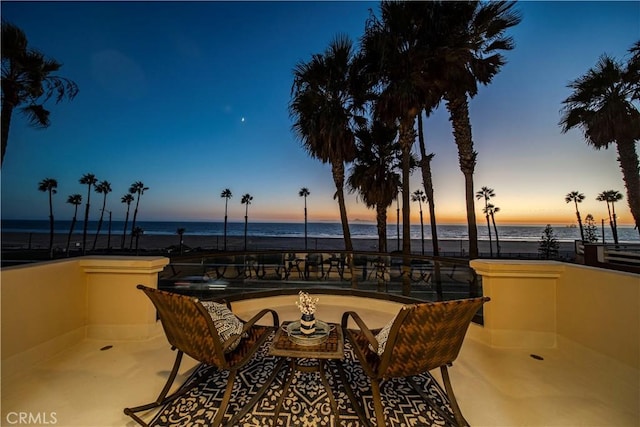 patio terrace at dusk featuring a water view