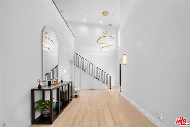 corridor featuring light hardwood / wood-style floors and a towering ceiling