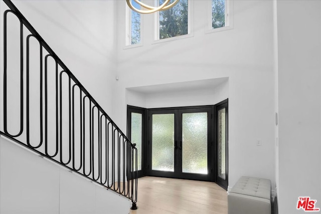 entrance foyer with a high ceiling, radiator heating unit, light hardwood / wood-style floors, and french doors