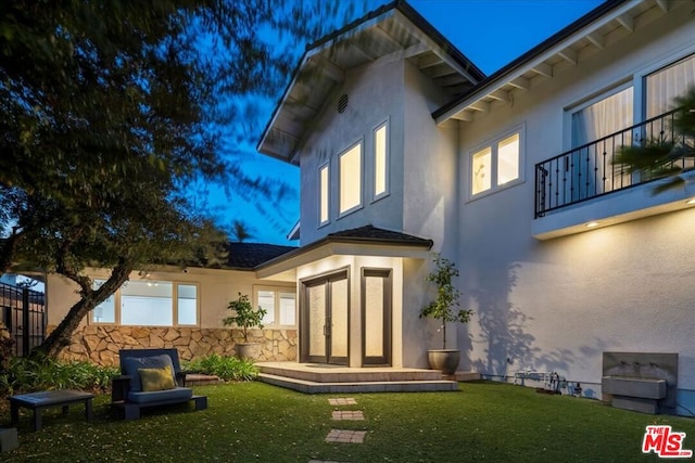 back of property with a yard and a balcony