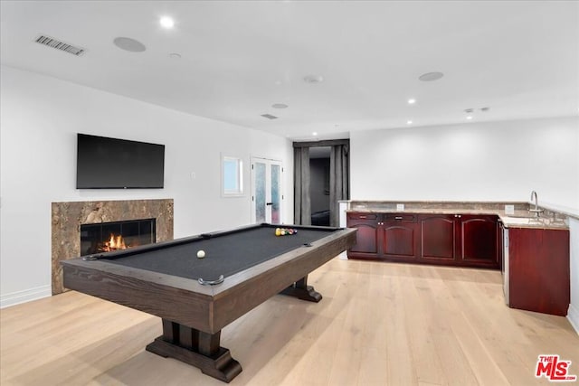 game room with sink, billiards, light wood-type flooring, and a high end fireplace