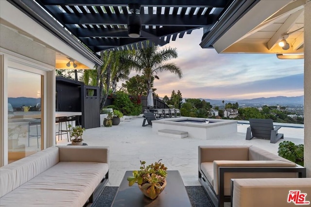 patio terrace at dusk featuring an outdoor hangout area, a mountain view, and a pergola