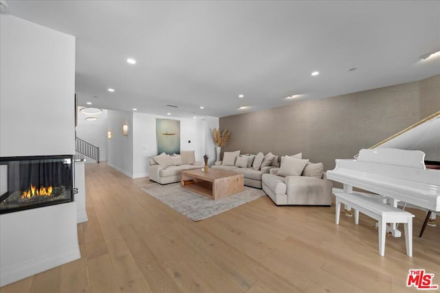 living room with a multi sided fireplace and light hardwood / wood-style flooring