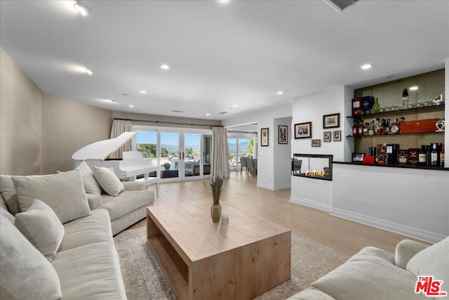 living room with a multi sided fireplace and light wood-type flooring