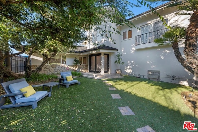 back of property featuring a balcony and a lawn