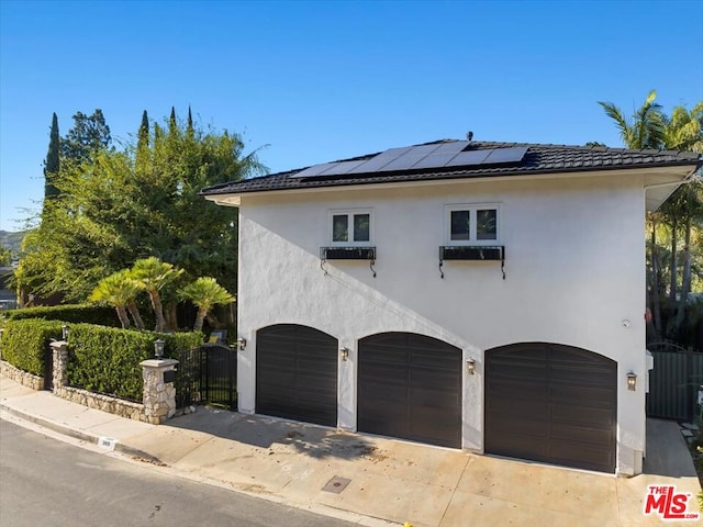 view of side of property with a garage and solar panels