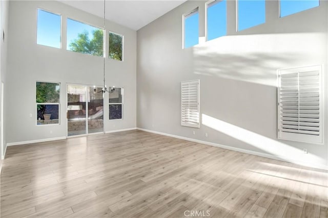 unfurnished living room with a towering ceiling, hardwood / wood-style flooring, and a notable chandelier