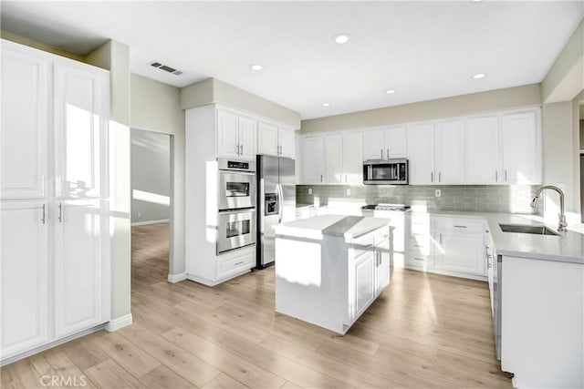 kitchen featuring white cabinets, a center island, stainless steel appliances, and sink