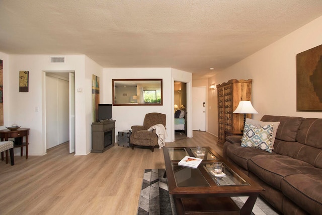 living room with a textured ceiling and light wood-type flooring