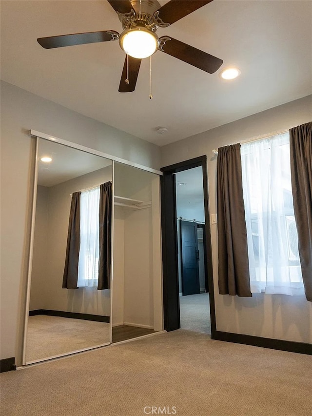 unfurnished bedroom featuring ceiling fan, a closet, and light colored carpet