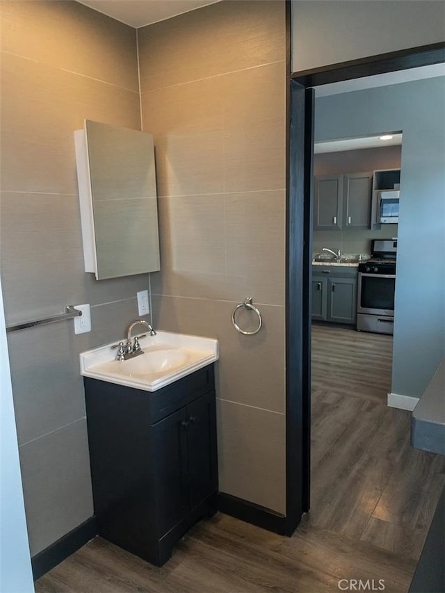 bathroom featuring hardwood / wood-style flooring, tile walls, and vanity