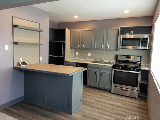 kitchen featuring gray cabinets, sink, kitchen peninsula, black appliances, and hardwood / wood-style flooring