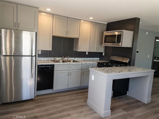 kitchen featuring sink, black appliances, gray cabinets, dark hardwood / wood-style floors, and light stone countertops