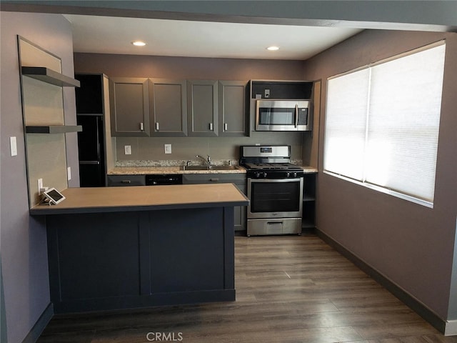 kitchen featuring sink, kitchen peninsula, gray cabinets, stainless steel appliances, and dark hardwood / wood-style flooring